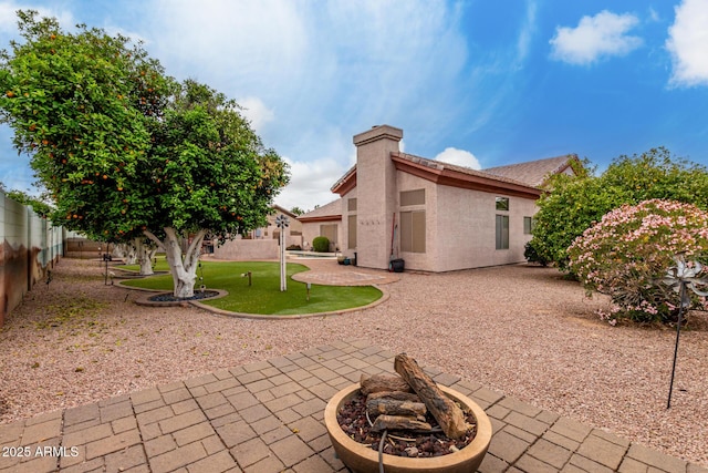 rear view of property with a fenced backyard, a fire pit, stucco siding, and a patio area