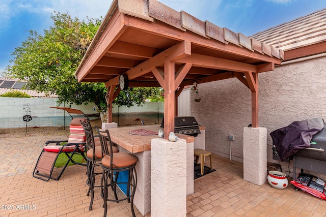view of patio with exterior kitchen, a fenced backyard, area for grilling, and outdoor dry bar