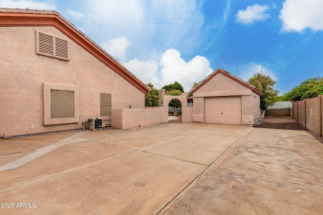 exterior space with a fenced backyard, a garage, concrete driveway, and stucco siding