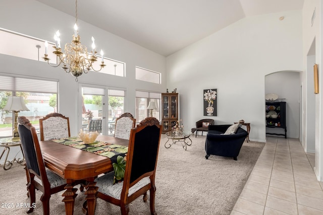 dining room with high vaulted ceiling, an inviting chandelier, arched walkways, and light tile patterned floors