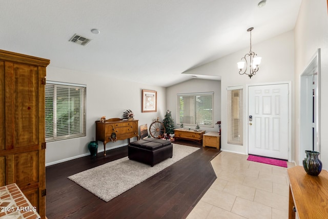 entryway with a notable chandelier, vaulted ceiling, and light wood-type flooring