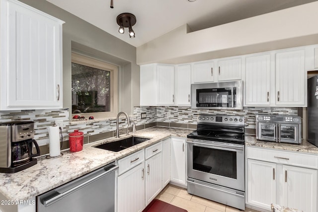 kitchen with light tile patterned flooring, sink, white cabinetry, appliances with stainless steel finishes, and light stone countertops