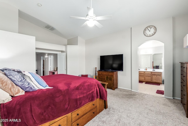 bedroom featuring lofted ceiling, light colored carpet, connected bathroom, and ceiling fan