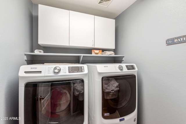 washroom featuring cabinets and washing machine and clothes dryer