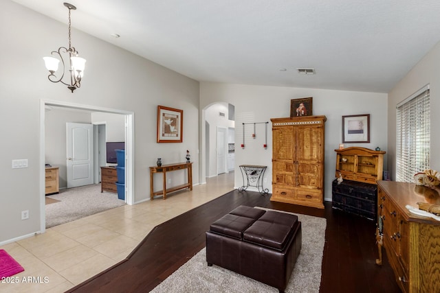 tiled living room with lofted ceiling and a notable chandelier