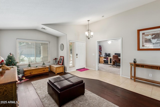 living room with lofted ceiling, a notable chandelier, and light hardwood / wood-style floors