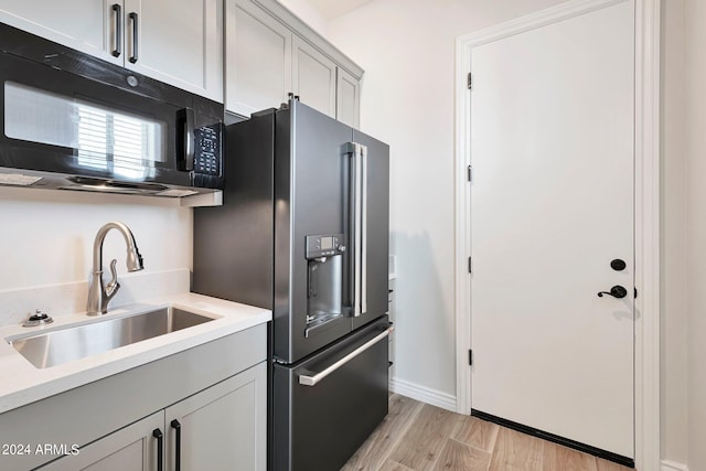 kitchen with gray cabinets, sink, high end refrigerator, and light hardwood / wood-style flooring