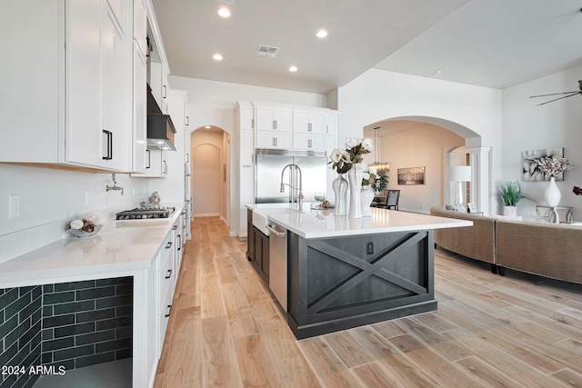 kitchen featuring white cabinetry, appliances with stainless steel finishes, premium range hood, and an island with sink