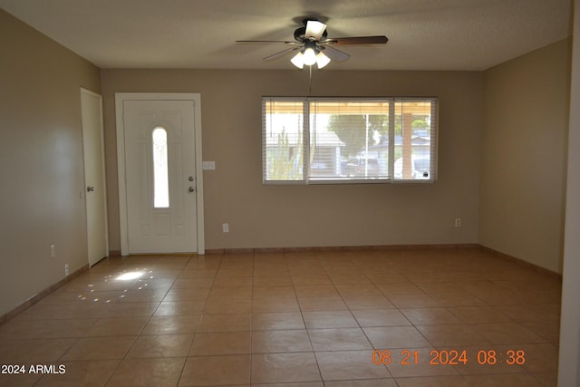 foyer entrance with a textured ceiling, ceiling fan, and light tile patterned flooring