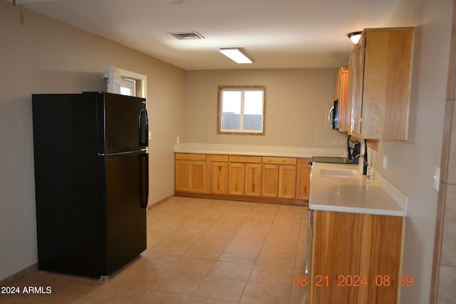 kitchen with black fridge, sink, and light tile patterned floors