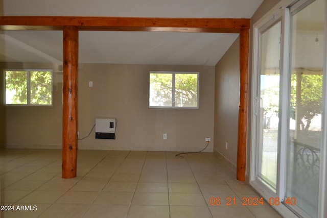 tiled empty room featuring lofted ceiling and heating unit