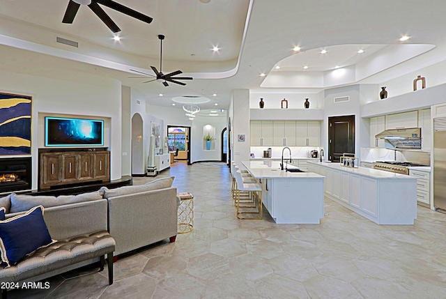 living room with ceiling fan, a raised ceiling, and sink