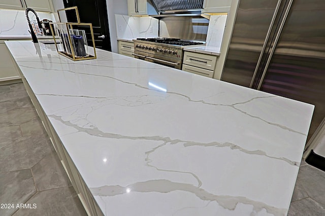 kitchen featuring stainless steel range, light stone countertops, and exhaust hood