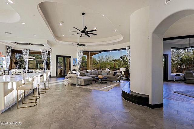 living room with ceiling fan, a raised ceiling, and plenty of natural light