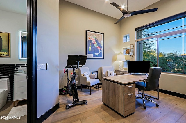 home office with light hardwood / wood-style flooring, ceiling fan, and a healthy amount of sunlight