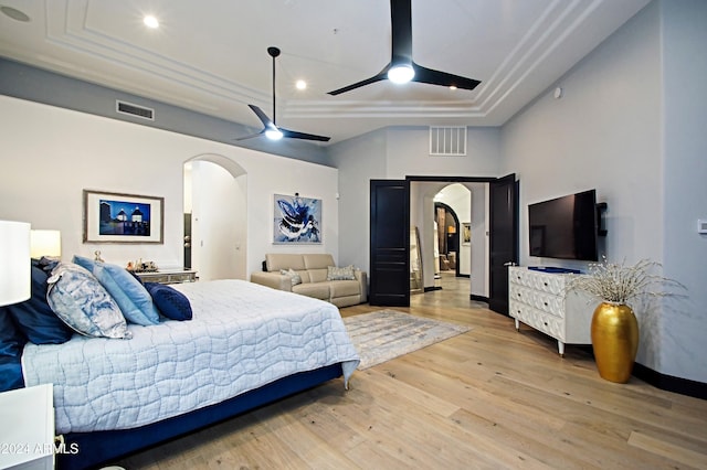 bedroom featuring a tray ceiling, ceiling fan, and light wood-type flooring