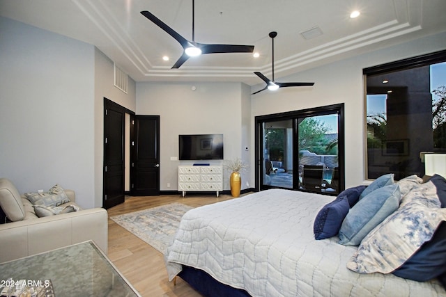 bedroom featuring a tray ceiling, access to exterior, ceiling fan, and hardwood / wood-style flooring