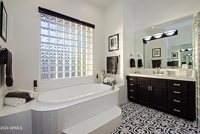 bathroom featuring tile patterned floors, tiled bath, and vanity