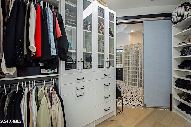 walk in closet with light hardwood / wood-style flooring