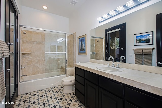 full bathroom featuring combined bath / shower with glass door, tile patterned floors, vanity, and toilet