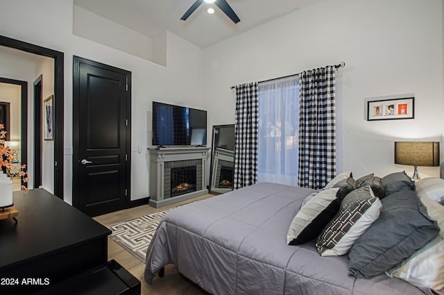 bedroom featuring ceiling fan, light hardwood / wood-style flooring, and a brick fireplace