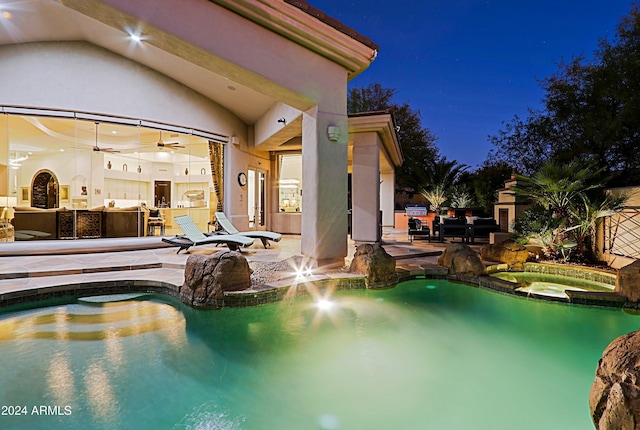 pool at twilight with an in ground hot tub and a patio