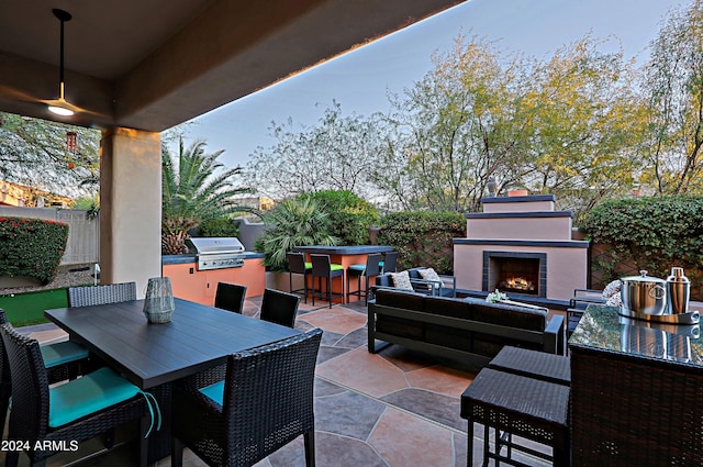 view of patio with an outdoor living space with a fireplace, a grill, and exterior bar