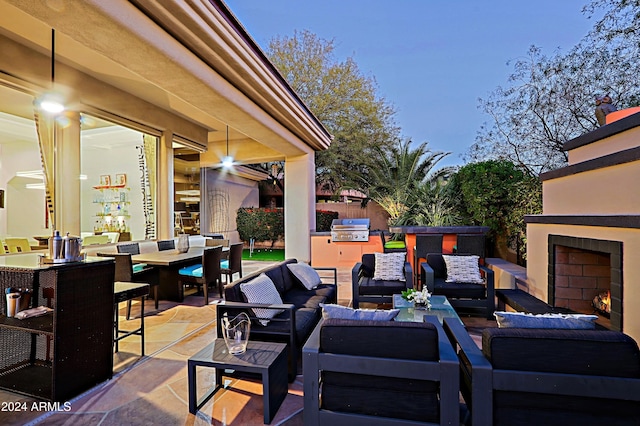 view of patio / terrace with an outdoor living space with a fireplace, grilling area, and exterior kitchen