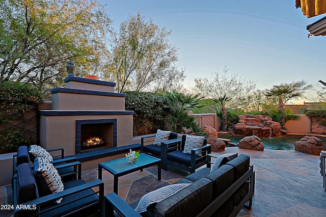 patio terrace at dusk with an outdoor living space with a fireplace