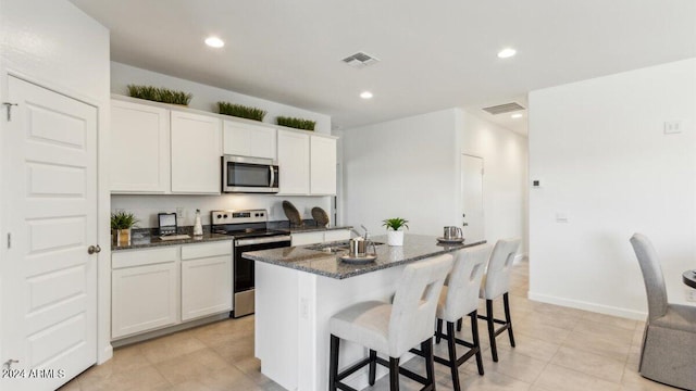 38100 W Bello Ln, Maricopa, AZ 85138 - kitchen with appliances with stainless steel finishes, a sink, a center island with sink, dark stone counters, and a breakfast bar