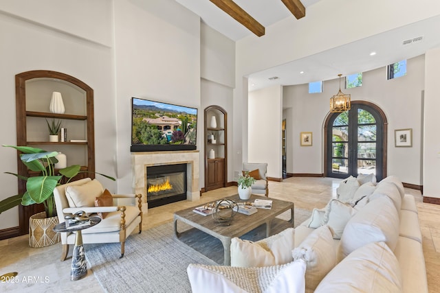 37334 N Winding Wash Trl, Carefree, AZ 85377 - living room featuring visible vents, a high ceiling, built in shelves, a tiled fireplace, and a notable chandelier