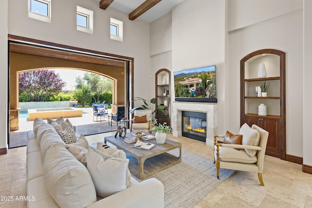 37334 N Winding Wash Trl, Carefree, AZ 85377 - living area with beamed ceiling, a high ceiling, a glass covered fireplace, and baseboards