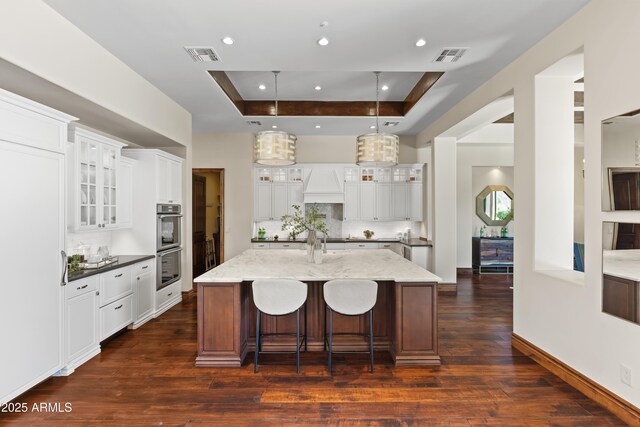 37334 N Winding Wash Trl, Carefree, AZ 85377 - kitchen featuring visible vents, a spacious island, a raised ceiling, custom range hood, and backsplash