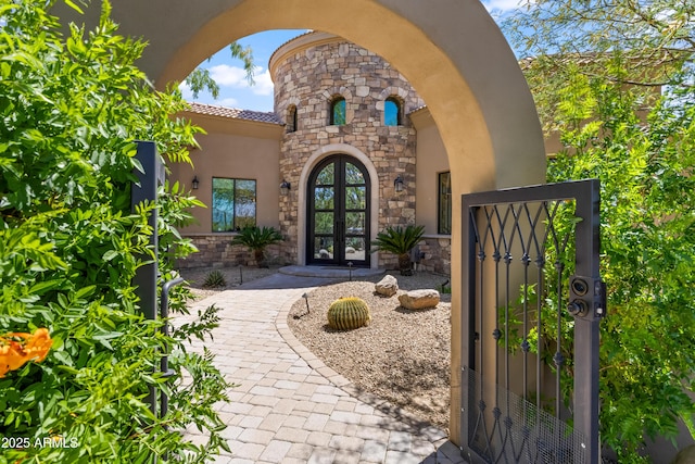 37334 N Winding Wash Trl, Carefree, AZ 85377 - property entrance featuring stone siding, stucco siding, french doors, a gate, and a tiled roof