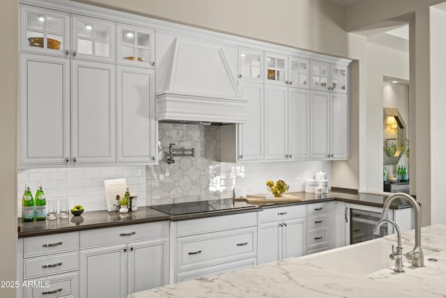 37334 N Winding Wash Trl, Carefree, AZ 85377 - kitchen with tasteful backsplash, black electric cooktop, a sink, custom range hood, and white cabinetry
