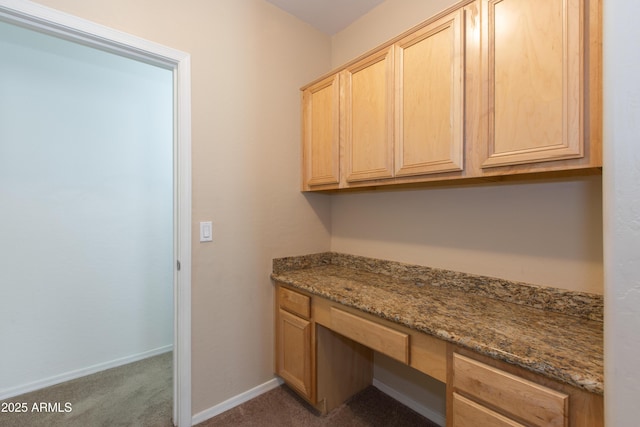 unfurnished office featuring carpet floors, baseboards, and built in study area