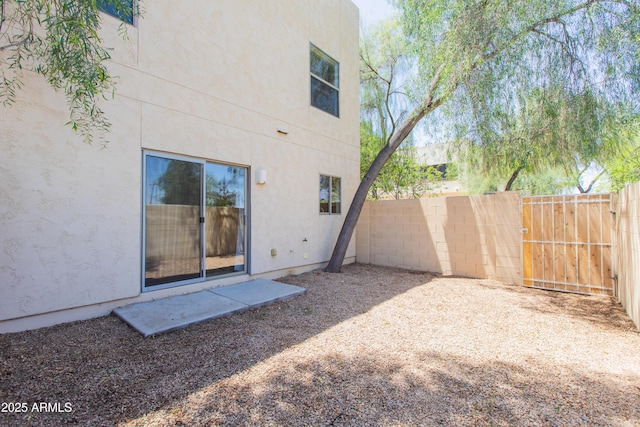 rear view of house featuring fence and stucco siding