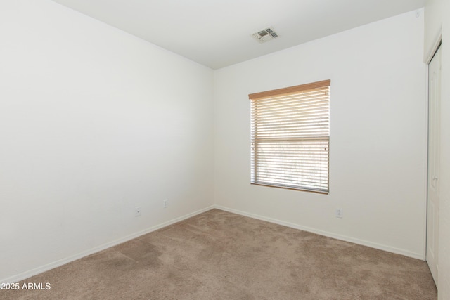 spare room with carpet floors, baseboards, and visible vents