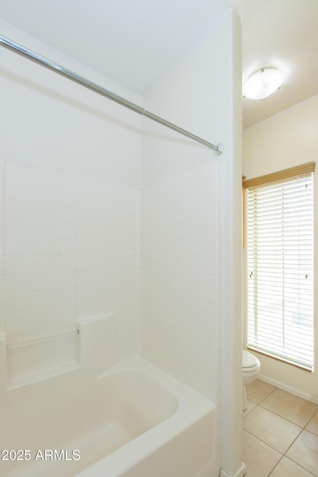 bathroom with toilet, tile patterned floors, plenty of natural light, and baseboards