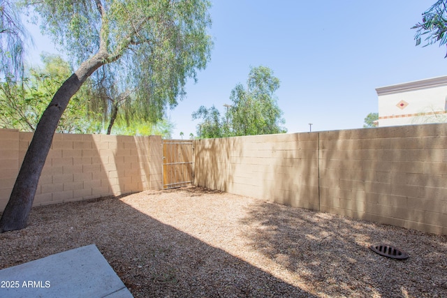 view of yard with a fenced backyard and a gate
