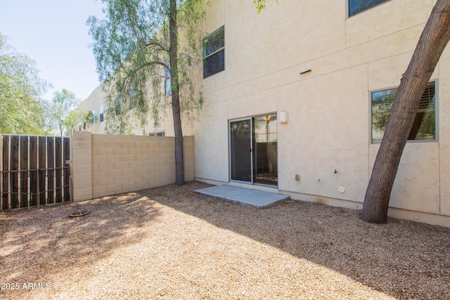 rear view of property featuring fence and stucco siding