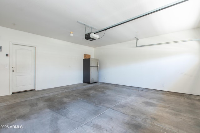 garage with a garage door opener and freestanding refrigerator