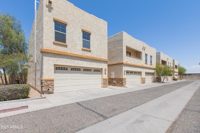 view of front facade featuring an attached garage, driveway, stucco siding, and stone siding
