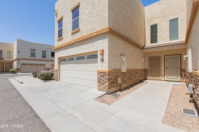 view of front of property with concrete driveway, an attached garage, stone siding, and stucco siding