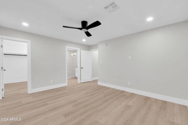 unfurnished bedroom with a closet, light hardwood / wood-style floors, a spacious closet, and ceiling fan