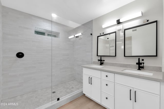 bathroom with hardwood / wood-style floors, vanity, and a tile shower