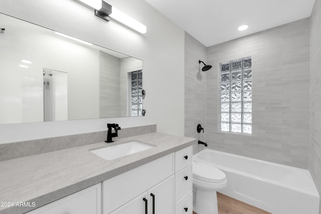 full bathroom with vanity, toilet, tiled shower / bath, and hardwood / wood-style flooring