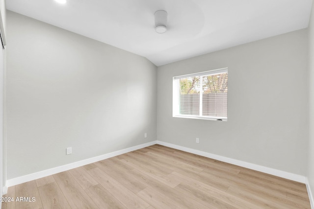 empty room with light wood-type flooring and vaulted ceiling