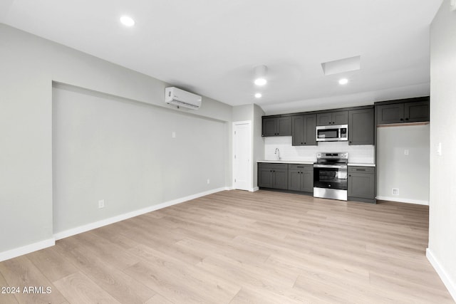 kitchen featuring light hardwood / wood-style floors, a wall unit AC, sink, and appliances with stainless steel finishes