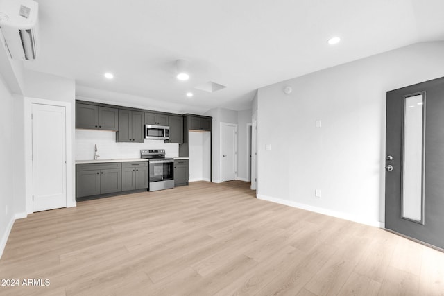 kitchen featuring stainless steel appliances, a wall mounted AC, light hardwood / wood-style floors, and sink